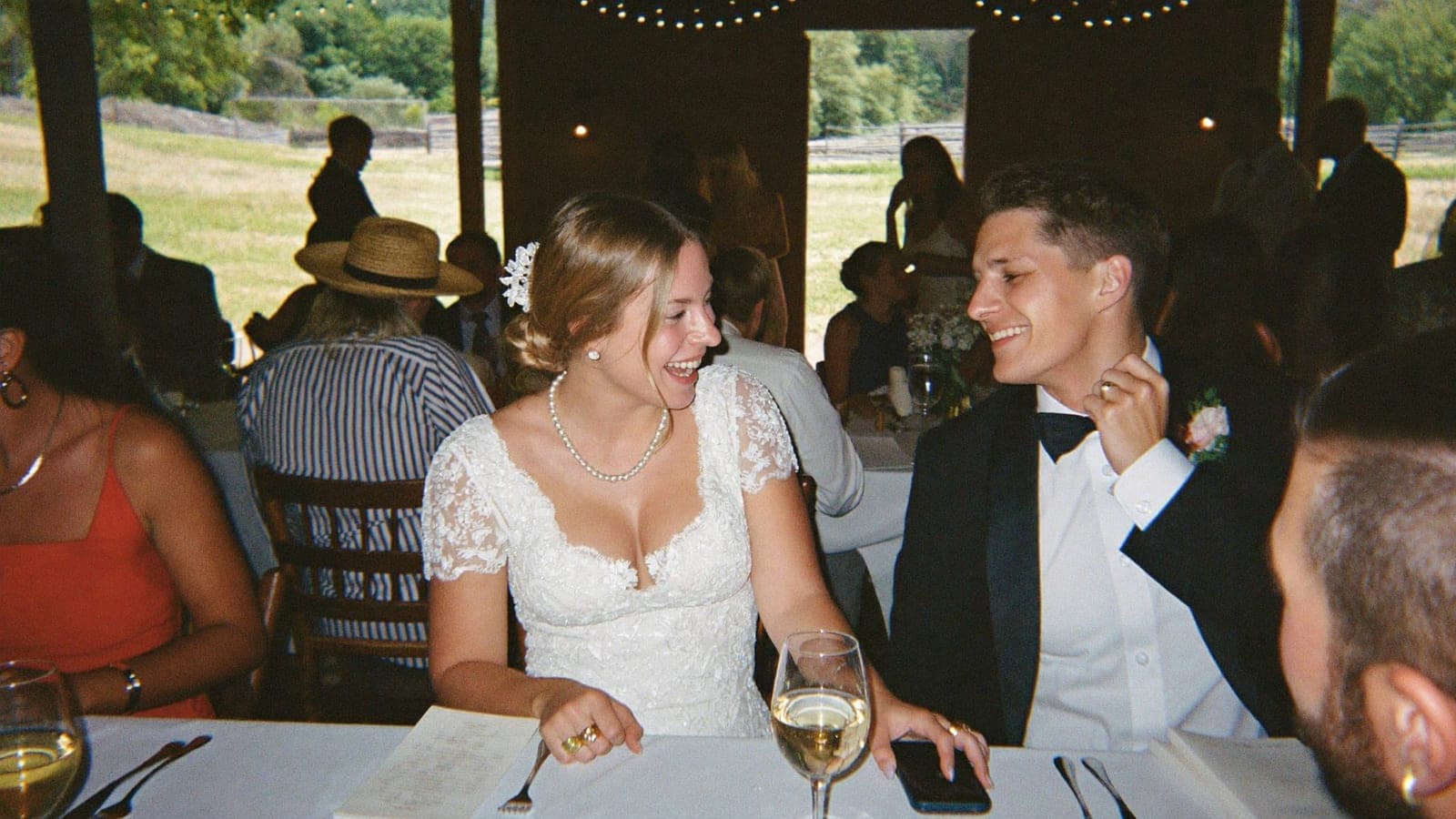 Guests laughing at the dinner table, a phone lying face down next to a glass