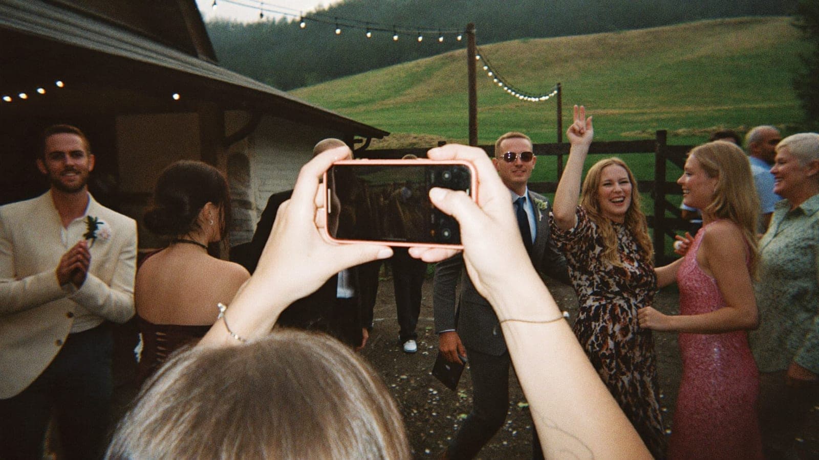 Ein Hochzeitsgast macht mit dem Handy ein Blitzfoto von tanzenden Freunden