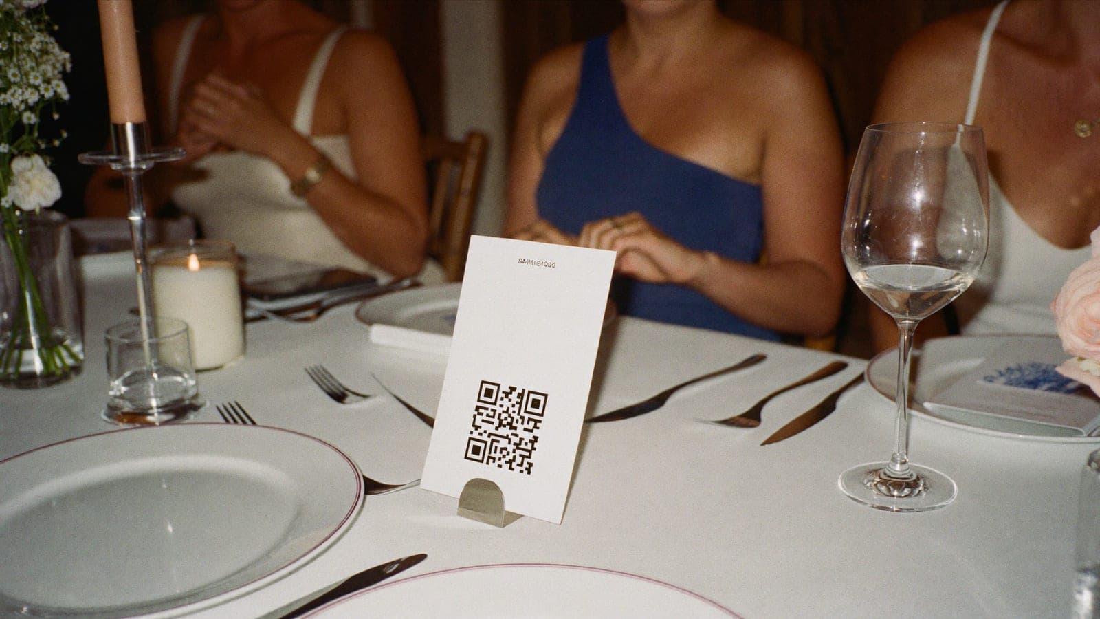 Ein QR-Code-Tischkärtchen zwischen Tellern und Blumen auf einer Hochzeitstafel
