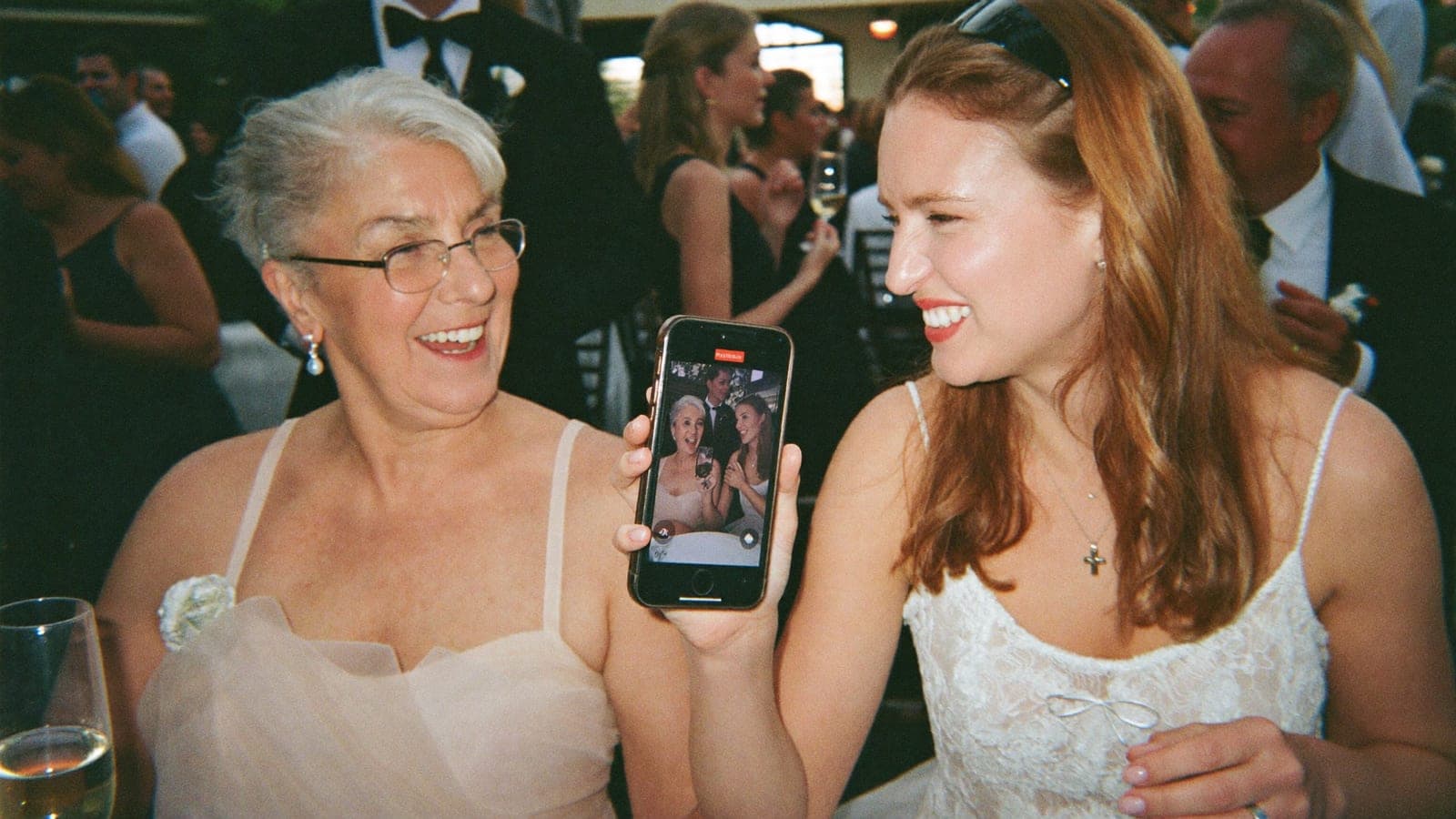 Gran and granddaughter laughing at a phone together at the wedding party