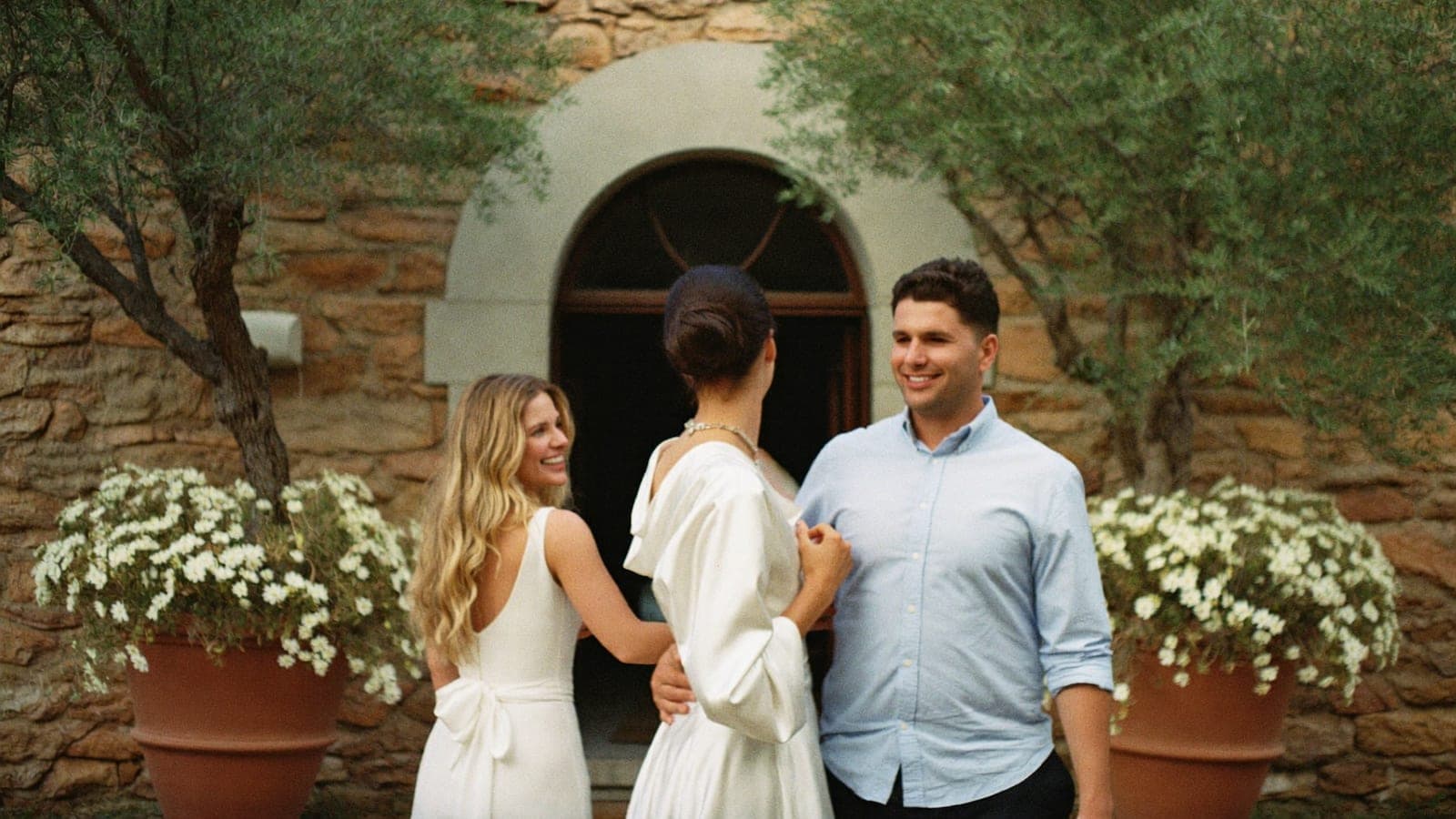 La novia recibe a una invitada que llega con su pareja a la entrada del salón