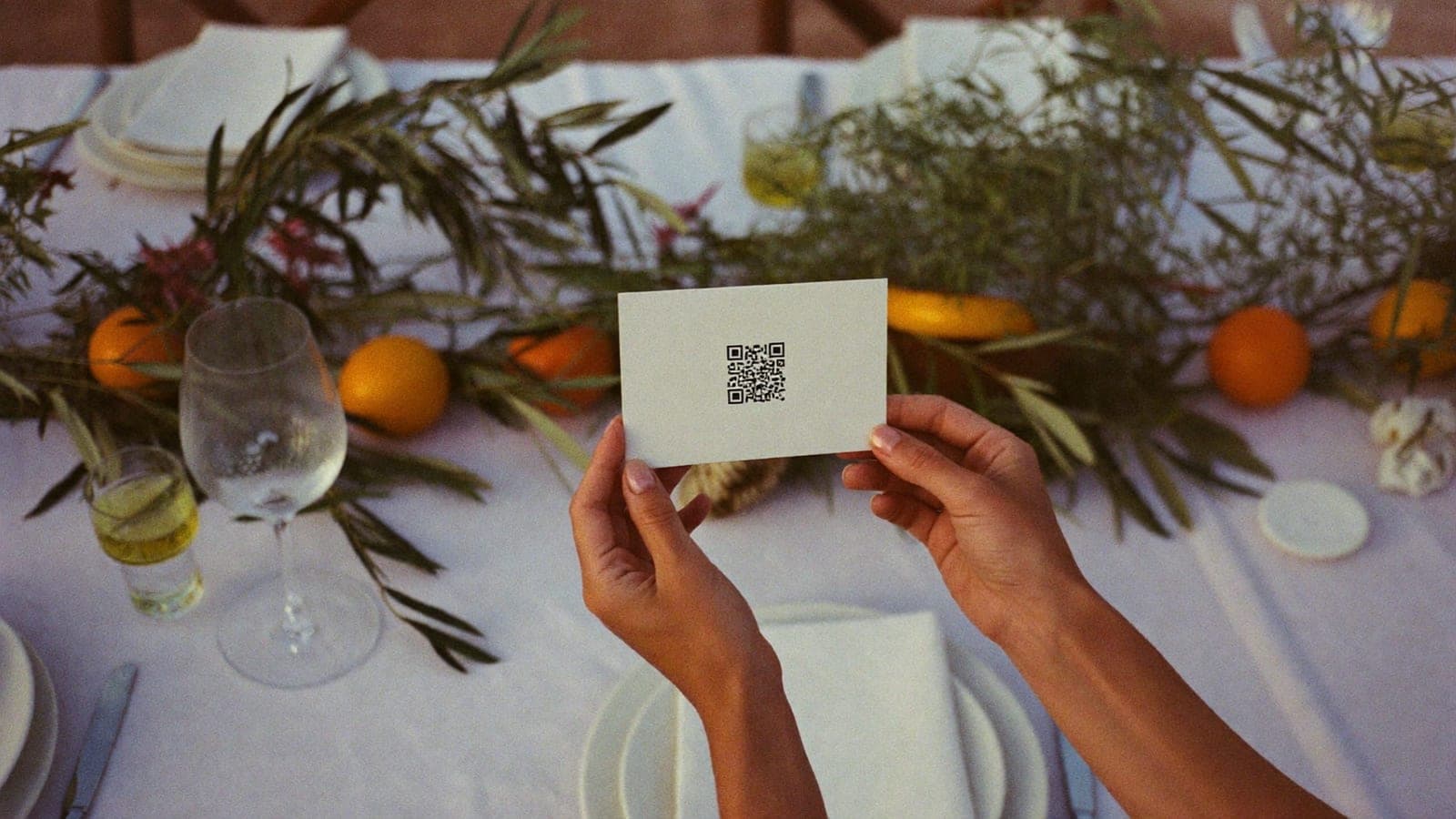 Una invitada sostiene en la mesa una tarjeta con el código QR