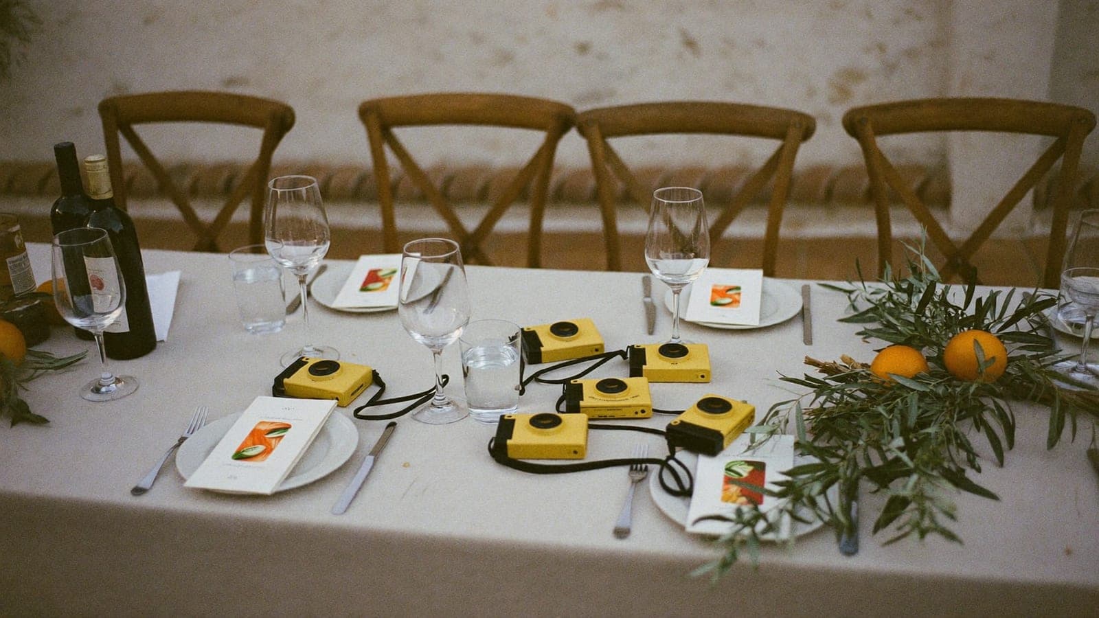 Cámaras desechables amarillas sobre la mesa del banquete entre copas y naranjas
