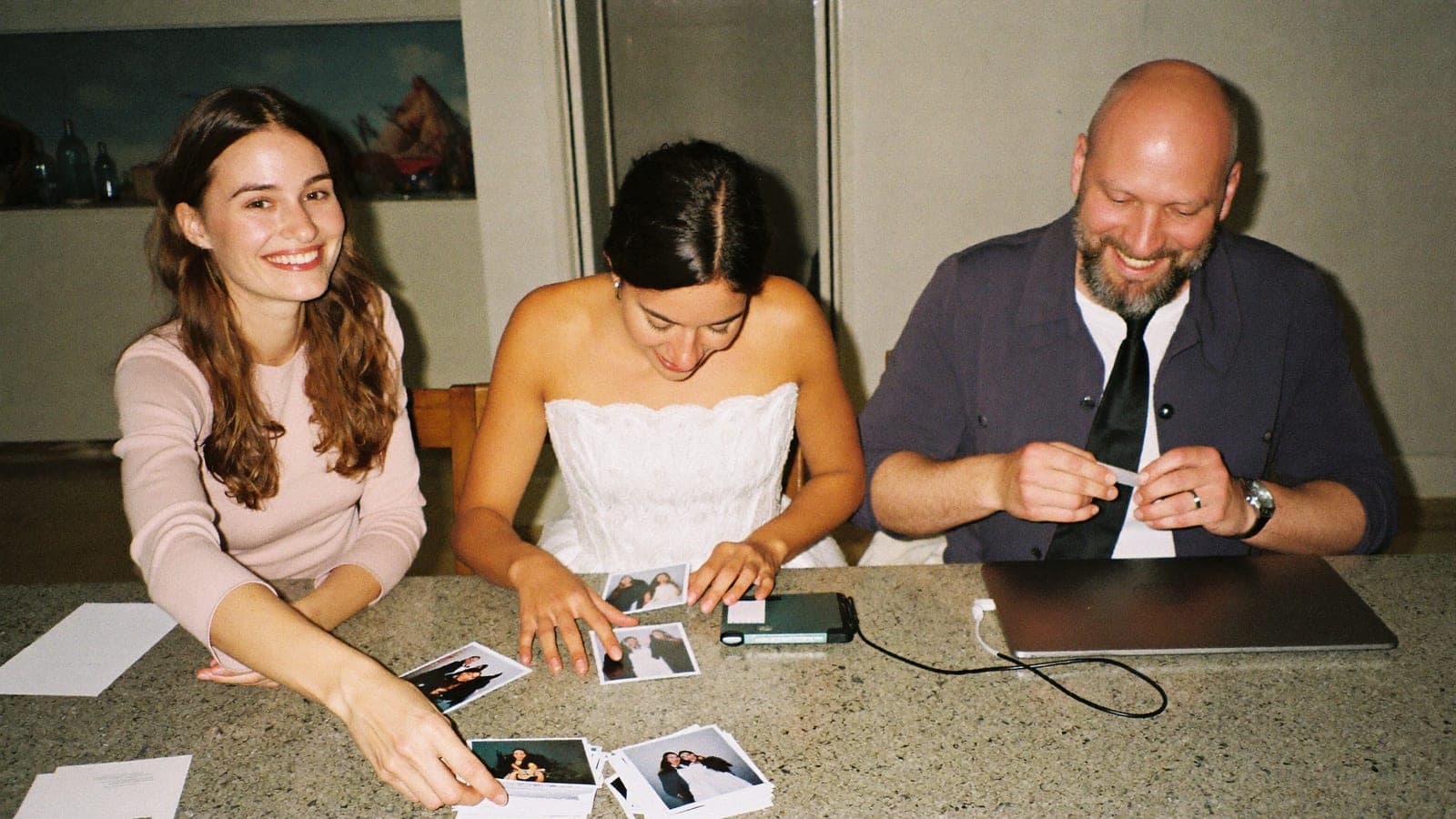 Fotos de boda impresas ordenadas en la mesa de la cocina junto a un disco duro externo