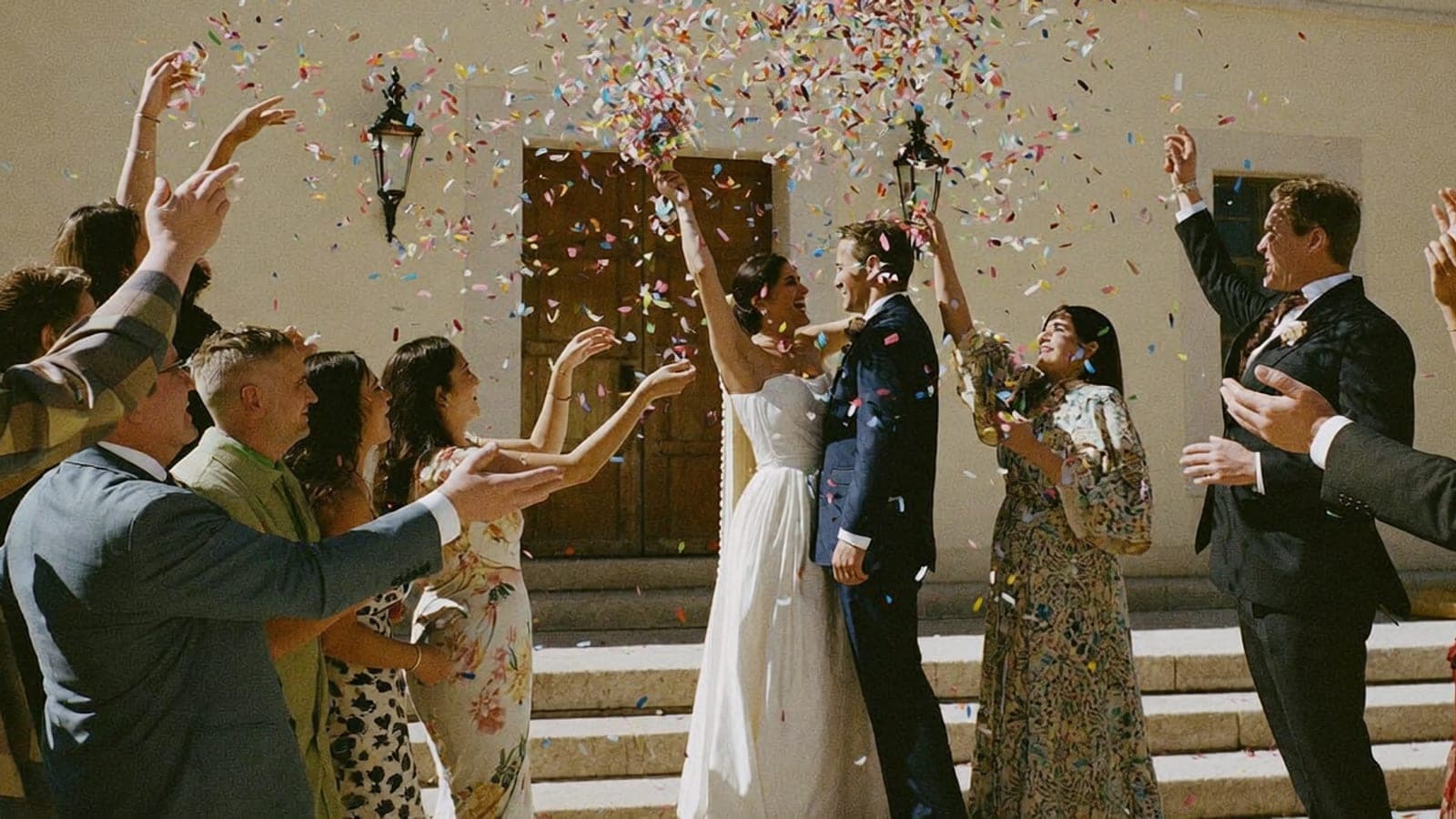 Un pequeño grupo de invitados lanza confeti a los novios en las escaleras del ayuntamiento
