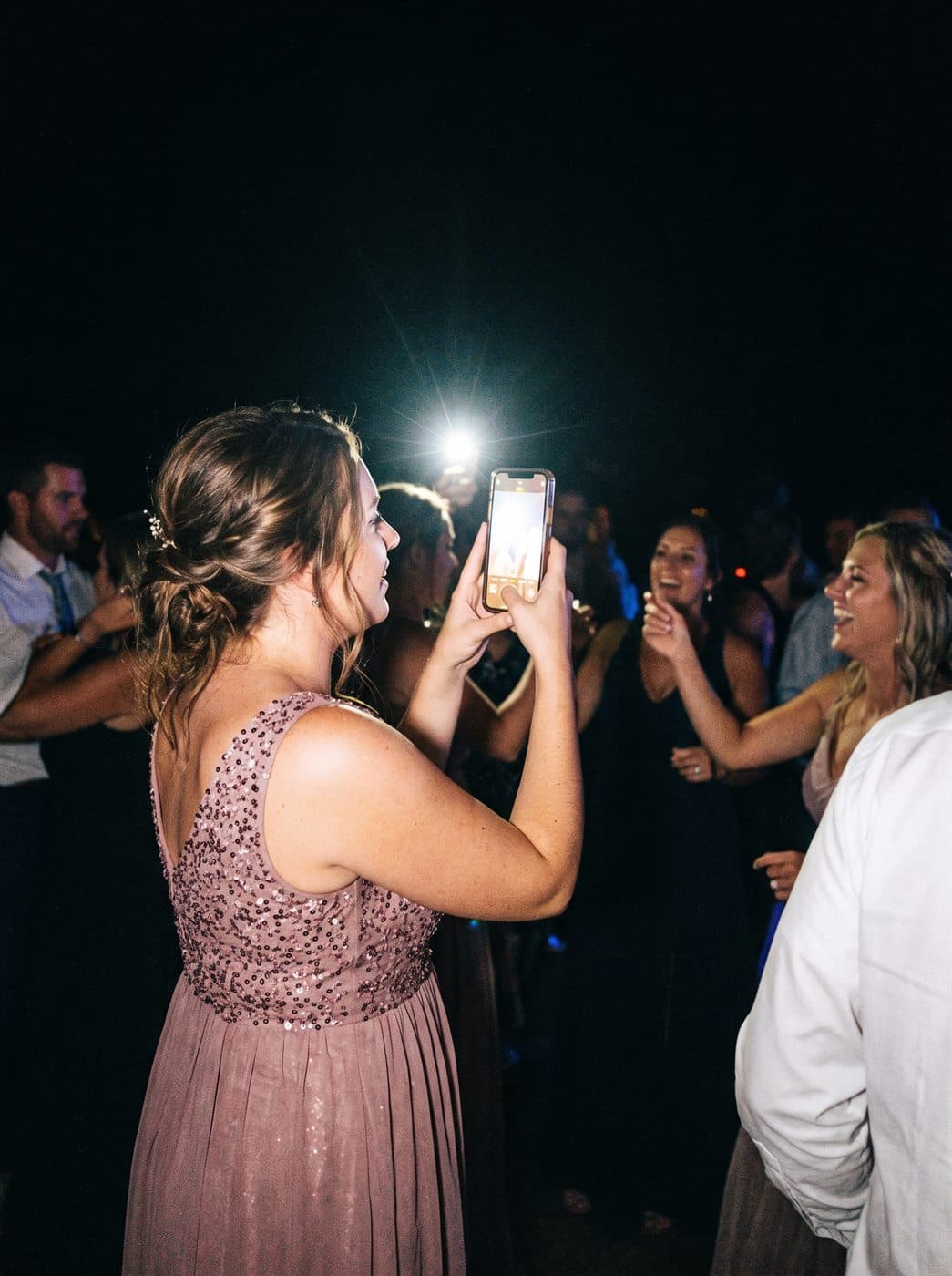 A guest taking a photo with her phone at the wedding