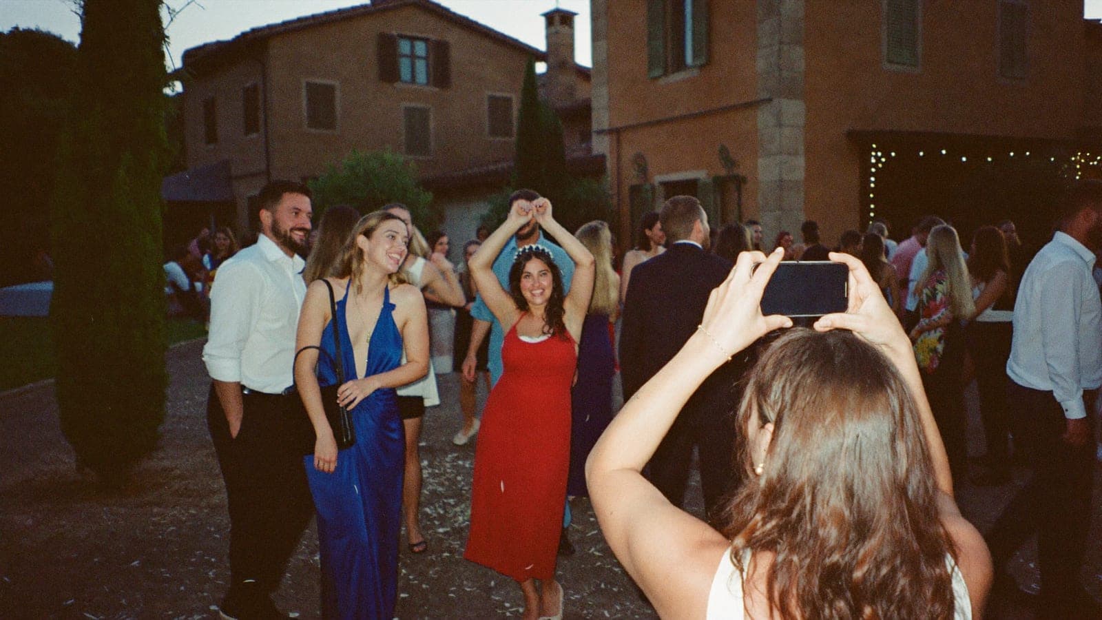 Un'invitata scatta col telefono una foto con il flash agli amici che ballano