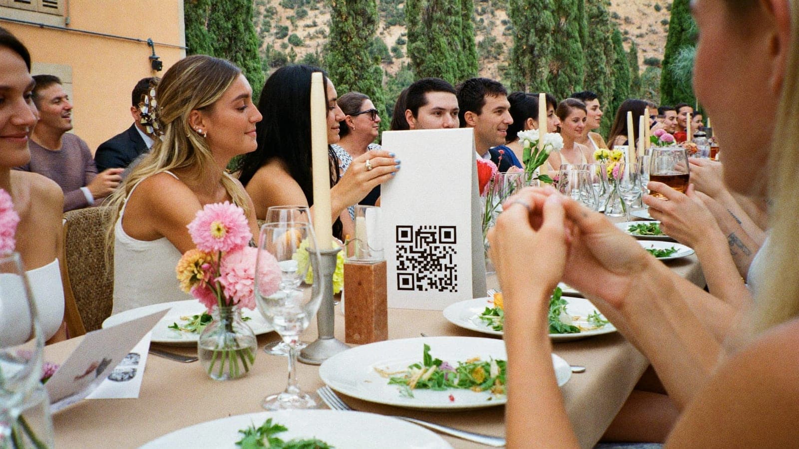 Un cartellino con QR code tra piatti e fiori su una tavola di matrimonio