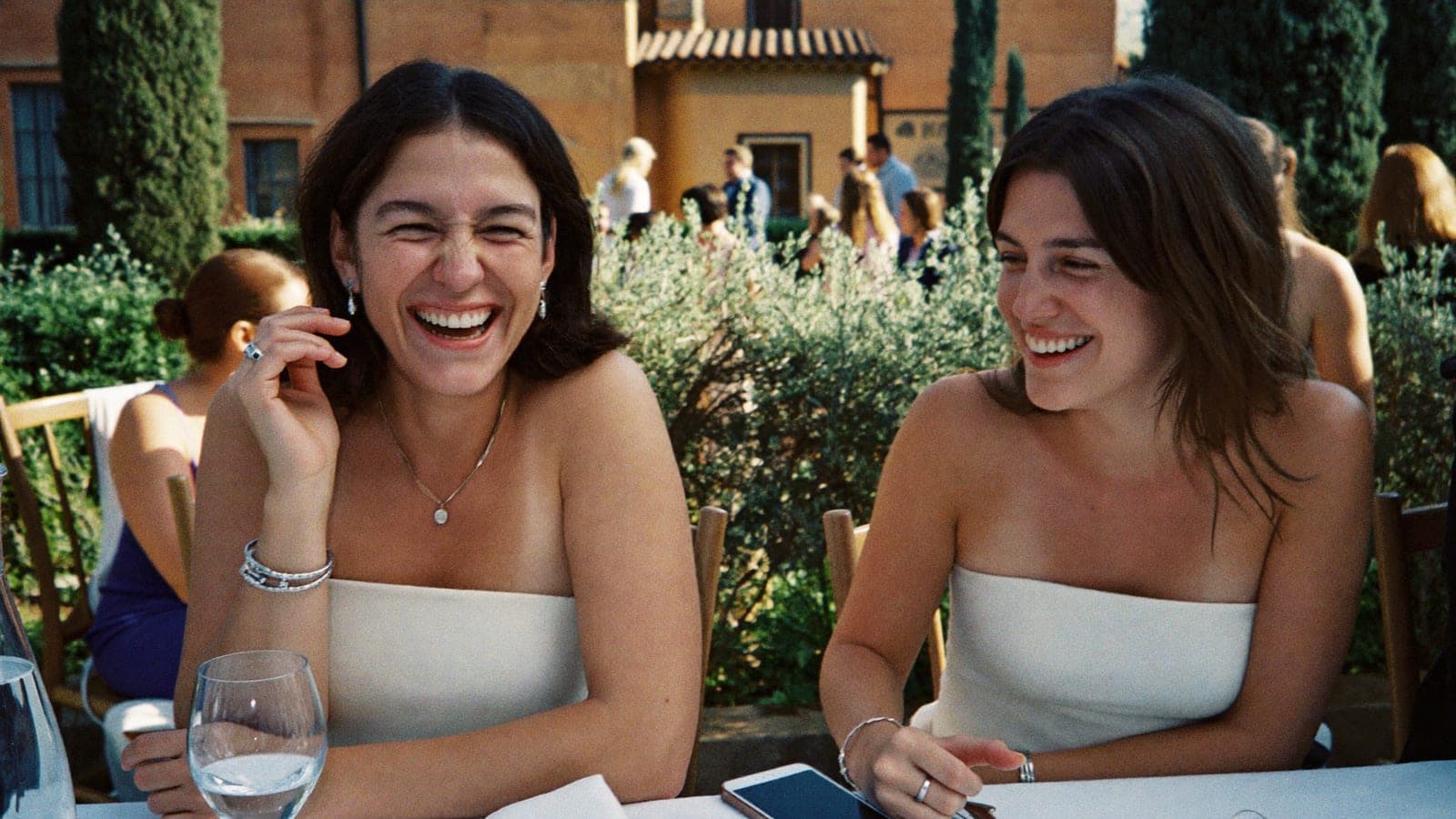 Invitati che ridono a tavola, un telefono a faccia in giù accanto a un bicchiere