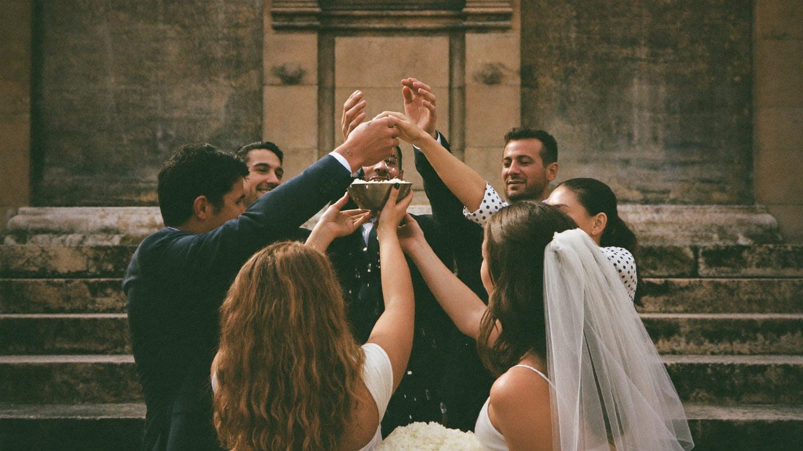 Un piccolo gruppo di invitati lancia i coriandoli sugli sposi sulla scalinata del comune