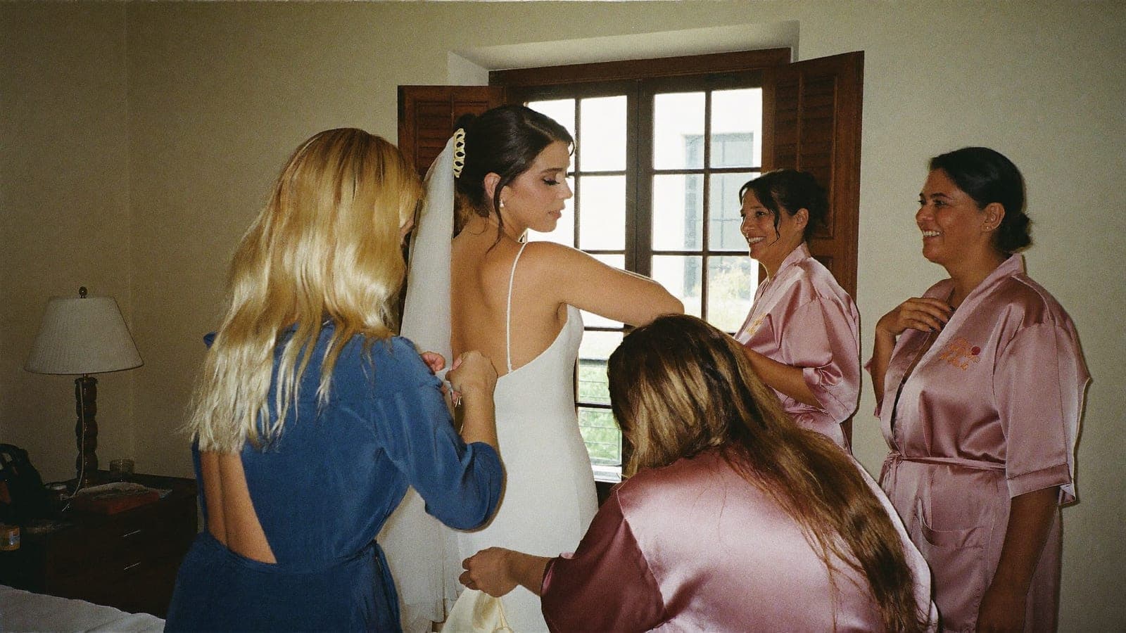 La madre della sposa abbottona l'abito vicino alla finestra