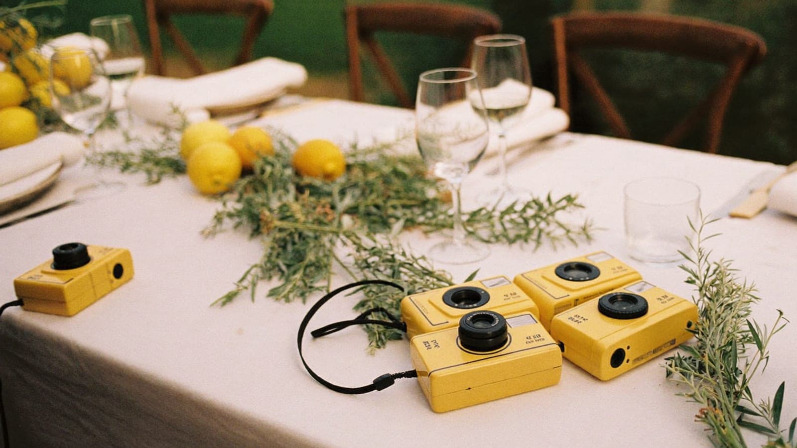 Fotocamere usa e getta gialle sul tavolo del ricevimento tra bicchieri e limoni