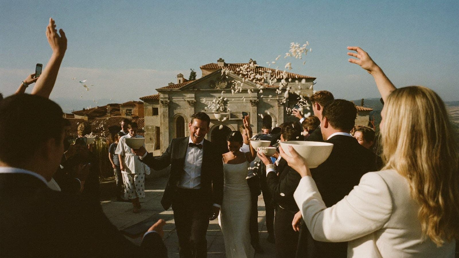 Gli sposi escono dalla chiesa mentre gli invitati lanciano il riso e scattano foto