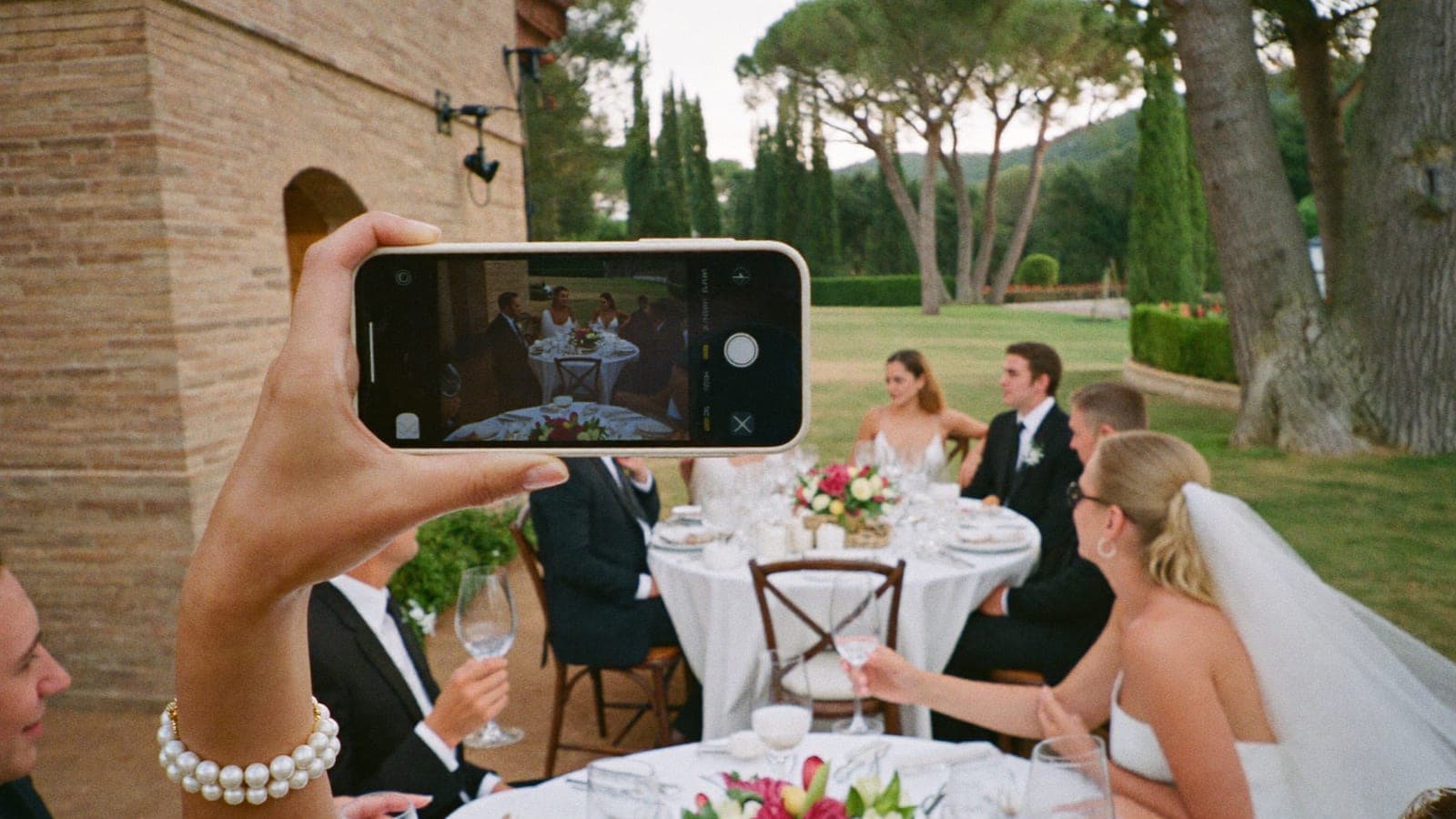 Un invitato filma con il telefono il discorso del testimone durante la cena