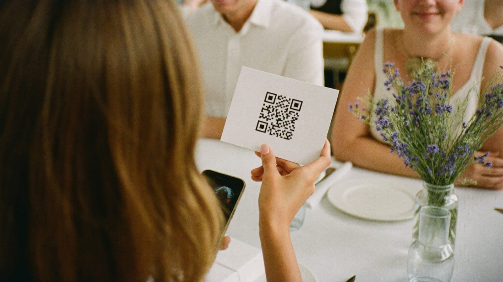 Gość przy weselnym stole trzyma karteczkę z samym kodem QR