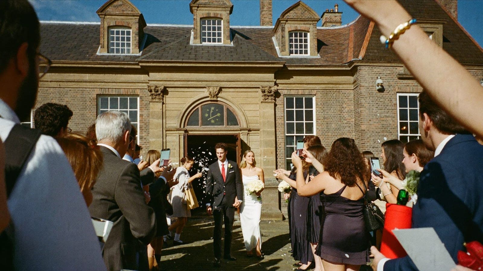 The couple walking out while guests throw confetti and take photos