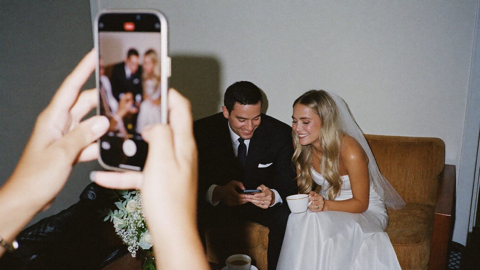 The newlyweds look at photos on a phone together the morning after the wedding