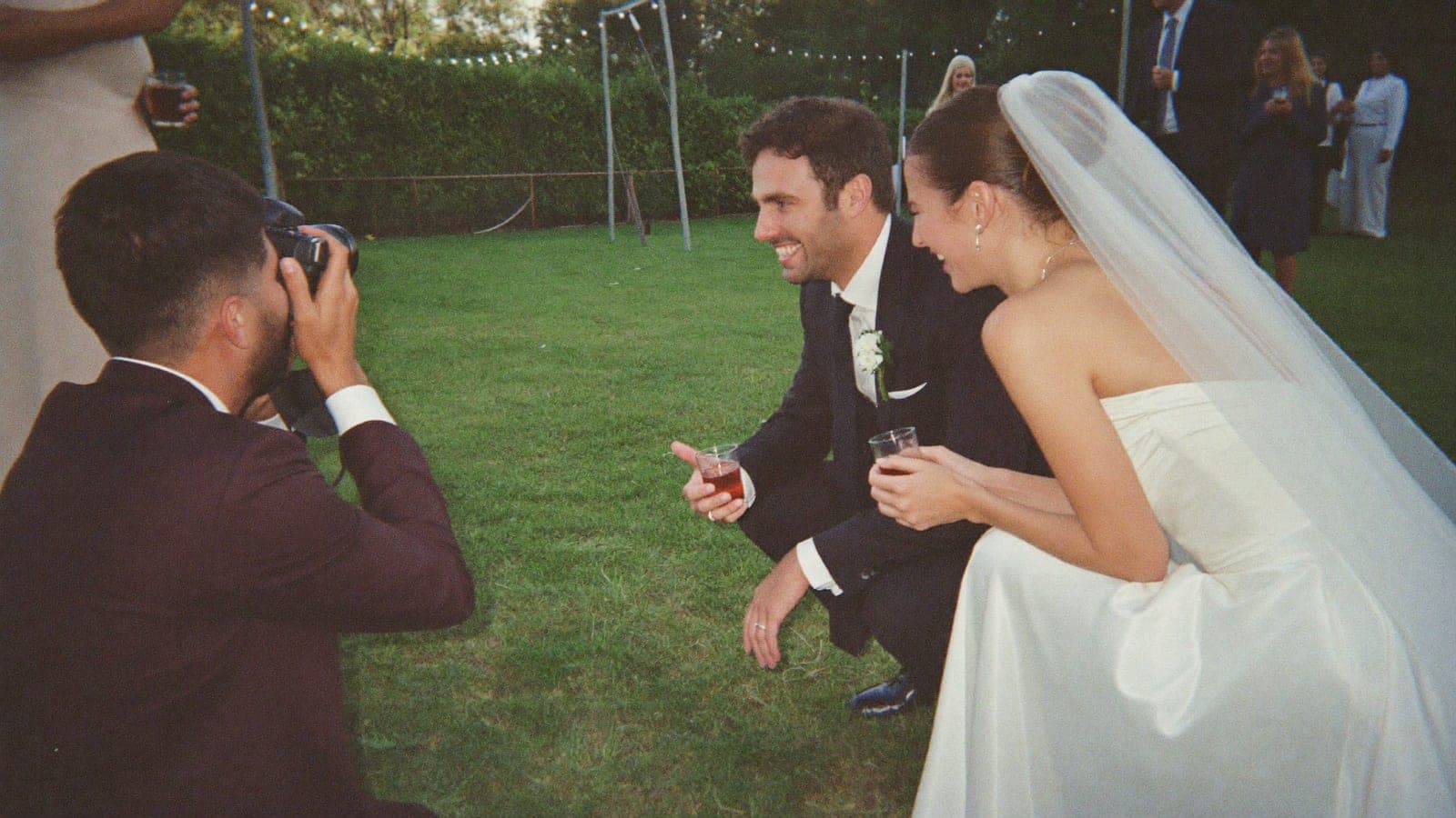 Çiftin bir arkadaşı bahçede gülen gelini fotoğraf makinesiyle çekiyor