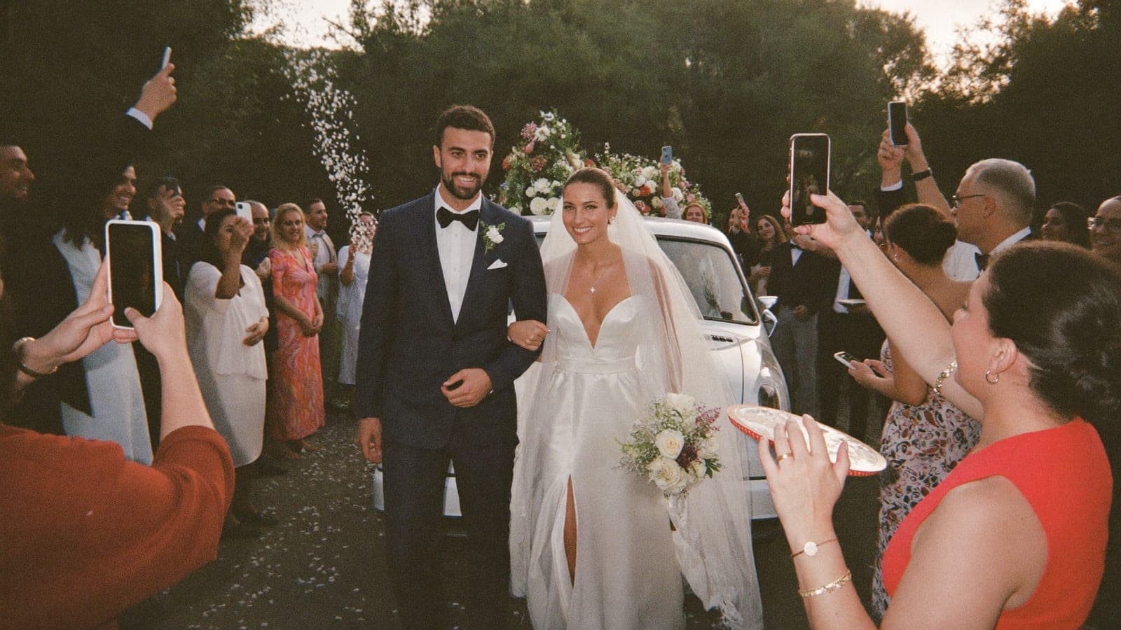 Gelin ve damat salondan çıkarken davetliler konfeti atıp fotoğraf çekiyor
