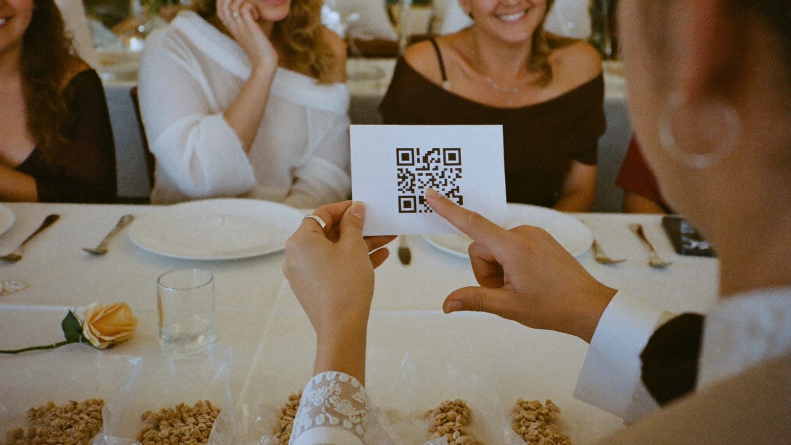 Bir davetli düğün masasında yalnızca QR kod bulunan kartı gösteriyor