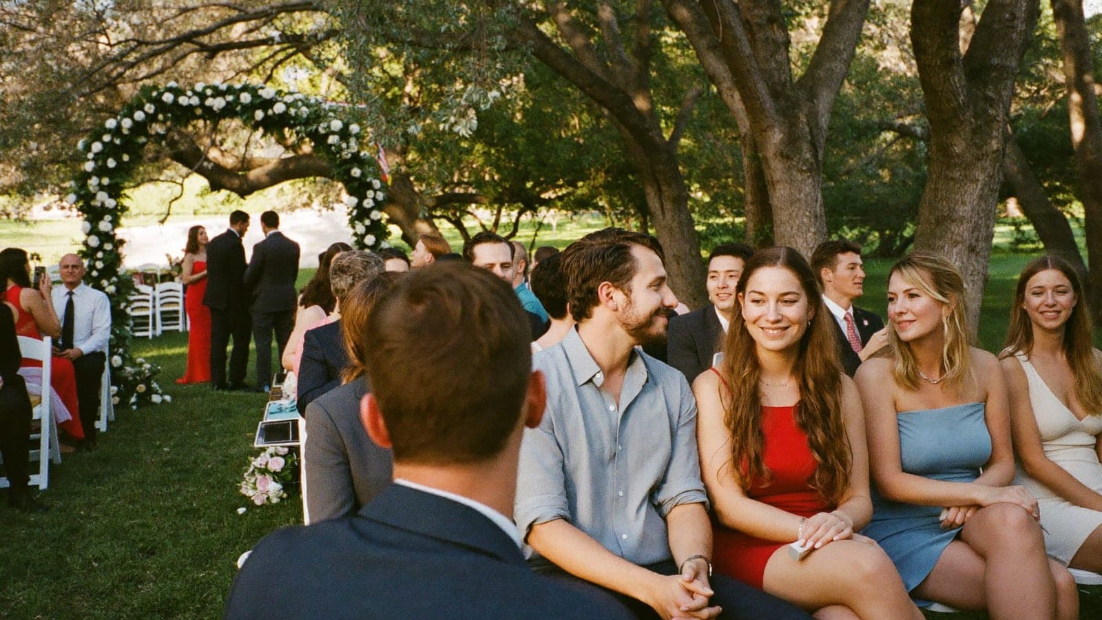 Guests on white chairs at an outdoor ceremony watching the couple, no phones in sight
