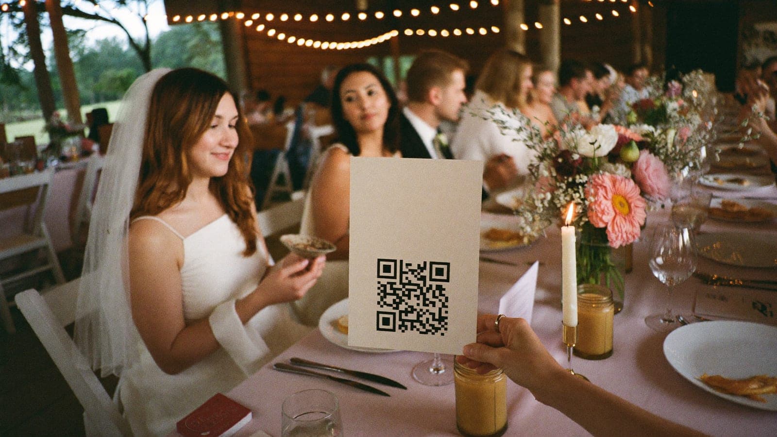 A QR code table card between the plates and flowers on a wedding table